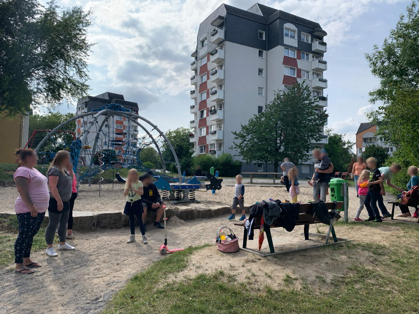 Familien und Kinder mit unkenntlich gemachten Gesichtern auf einem Spielplatz vor Wohnhäusern der Margarethenhöhe